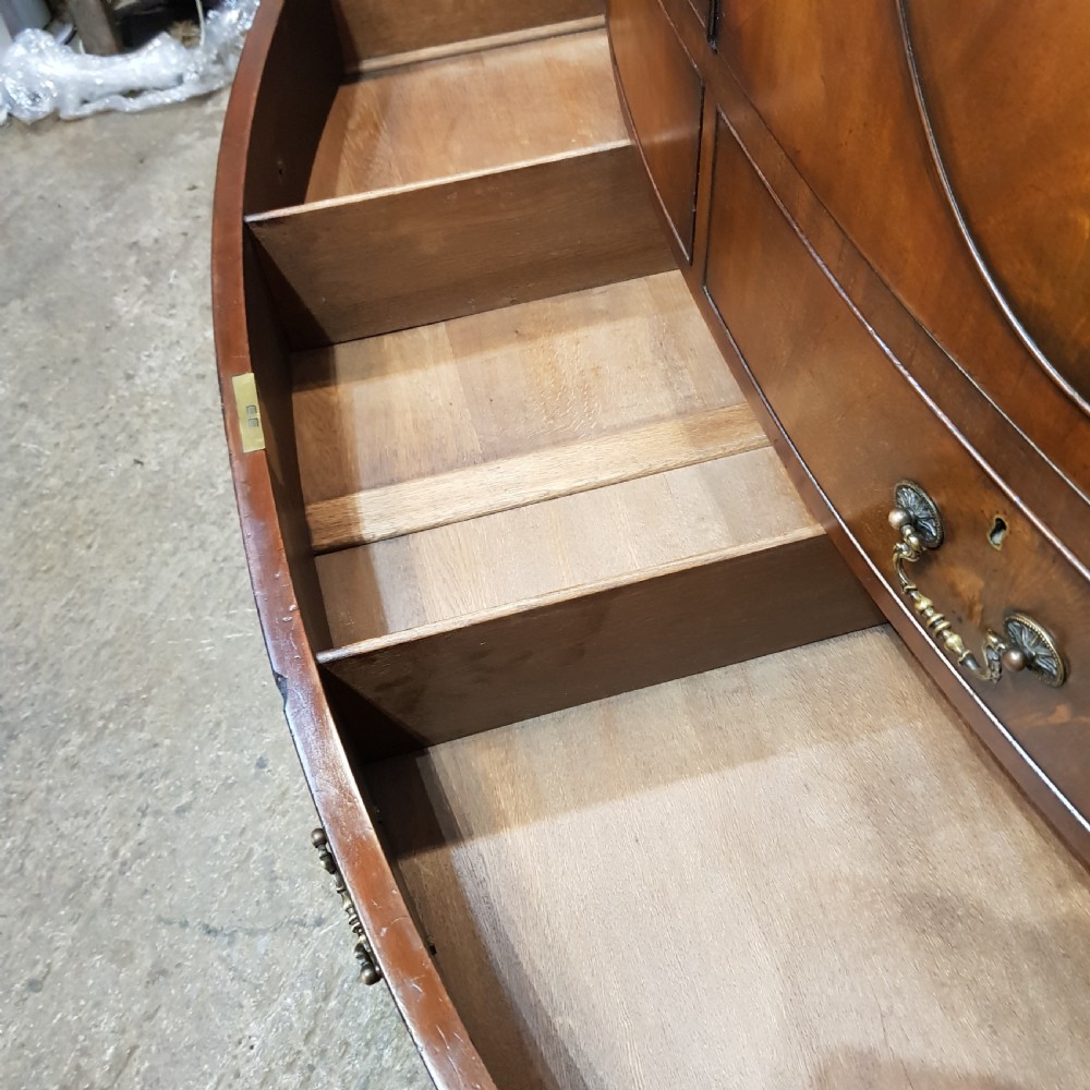 A large mahogany breakfront triple wardrobe featuring oval flame mahogany veneer panels on the doors and a central chest of drawers. View XIII
