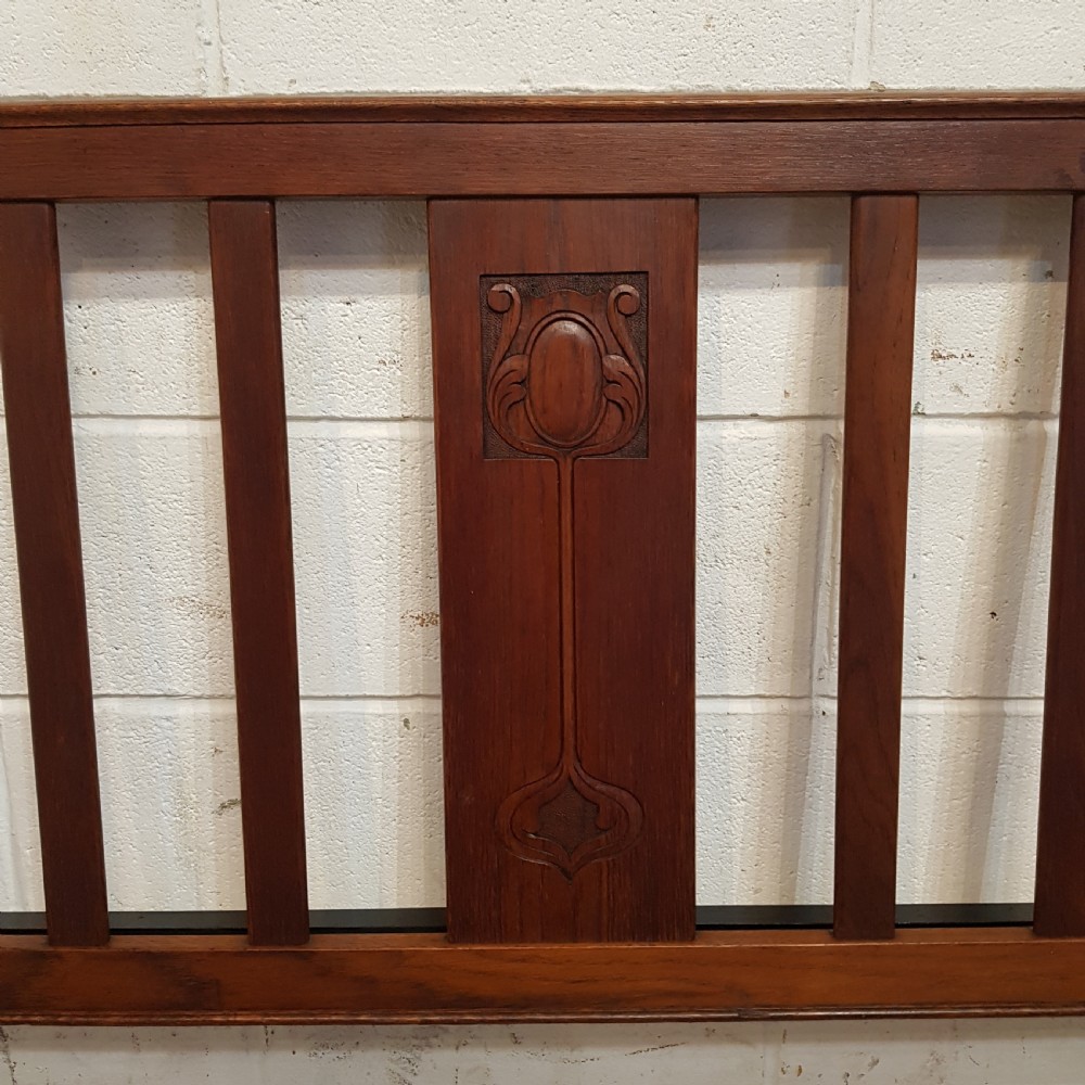 An Edwardian oak bedstead featuring slatted timber headboard and footboard panels with a central carved motif. View IV