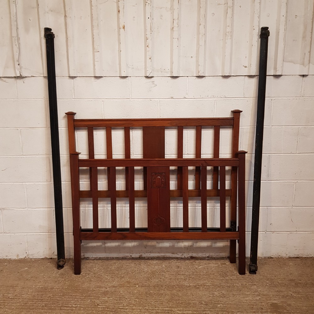 An Edwardian oak bedstead featuring slatted timber headboard and footboard panels with a central carved motif. View II