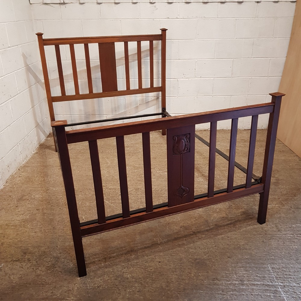 An Edwardian oak bedstead featuring slatted timber headboard and footboard panels with a central carved motif.