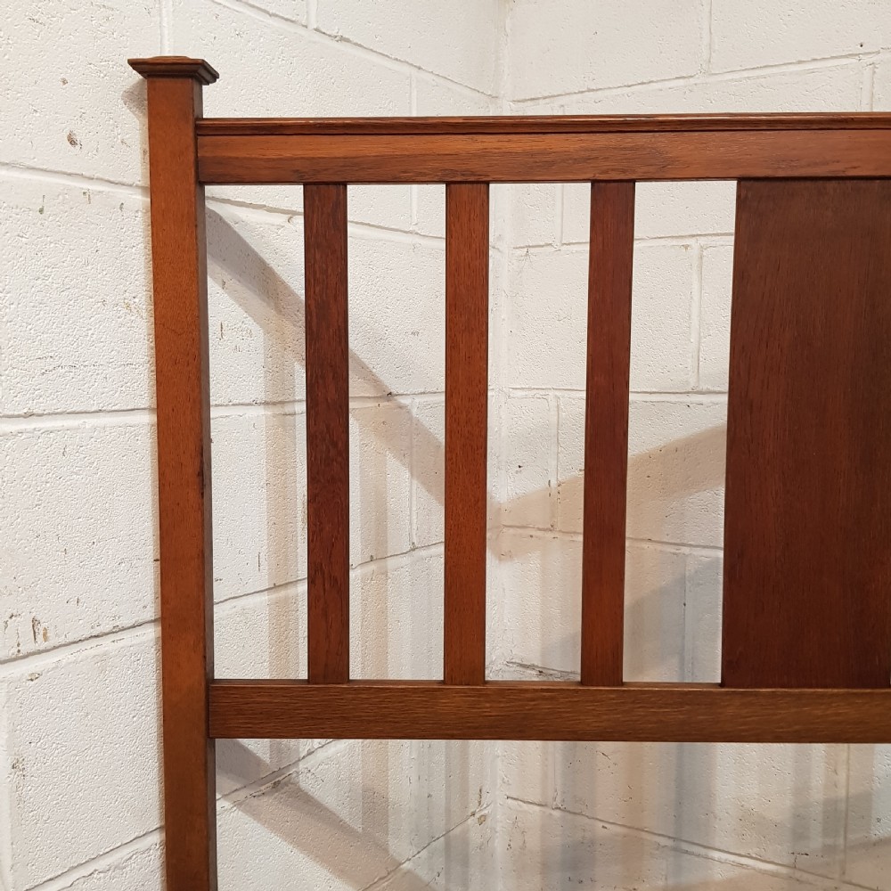 An Edwardian oak bedstead featuring slatted timber headboard and footboard panels with a central carved motif. View V