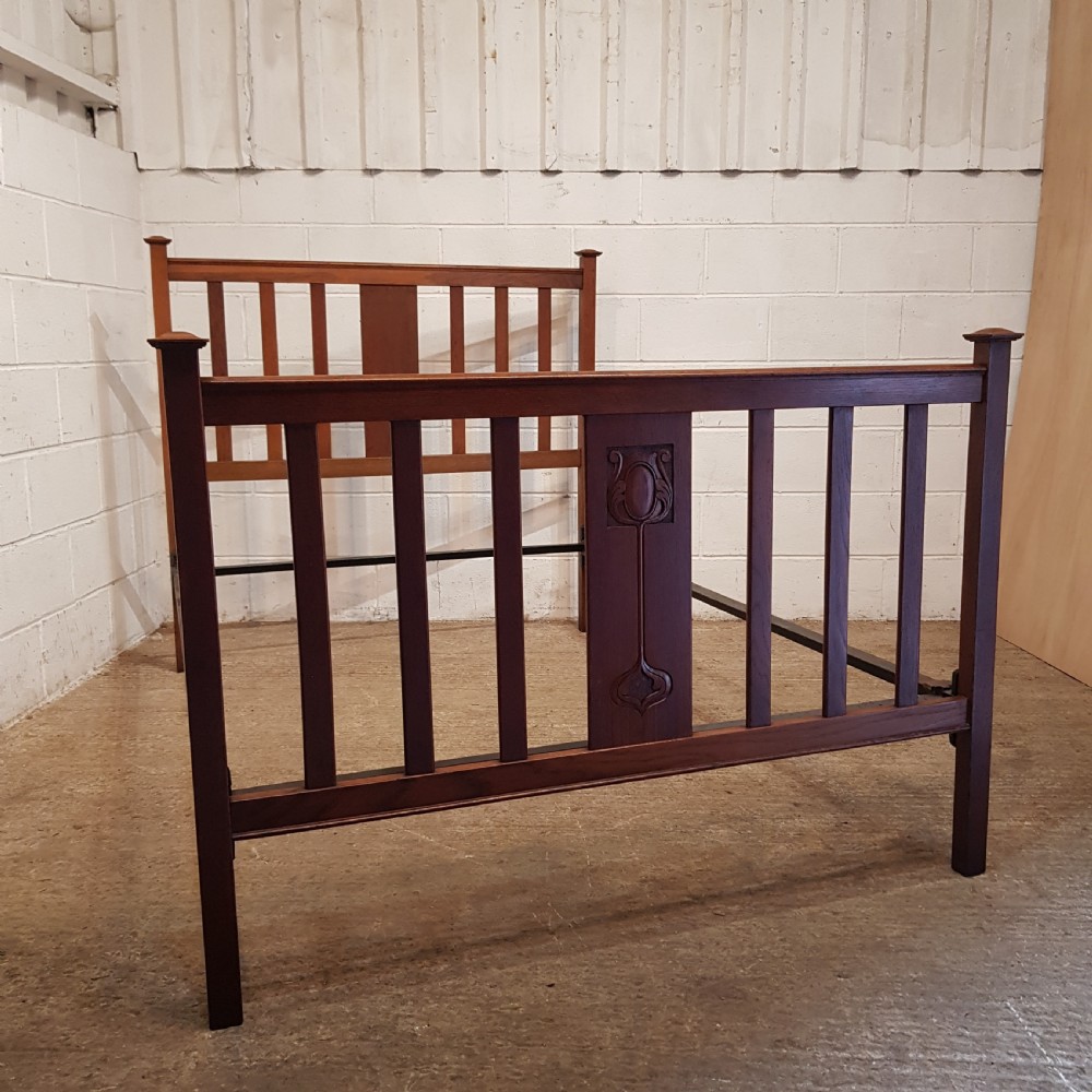 An Edwardian oak bedstead featuring slatted timber headboard and footboard panels with a central carved motif. View VI
