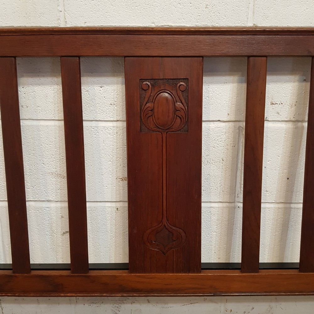 An Edwardian oak bedstead featuring slatted timber headboard and footboard panels with a central carved motif. View VII