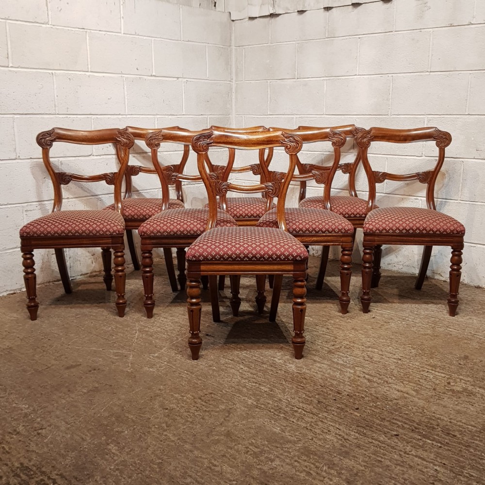 A set of carved walnut Victorian dining chairs featuring red patterned upholstered seats and turned front legs.