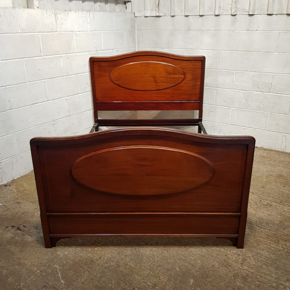 An Edwardian mahogany double bedstead featuring curved top rails and recessed oval panels on both the headboard and footboard.