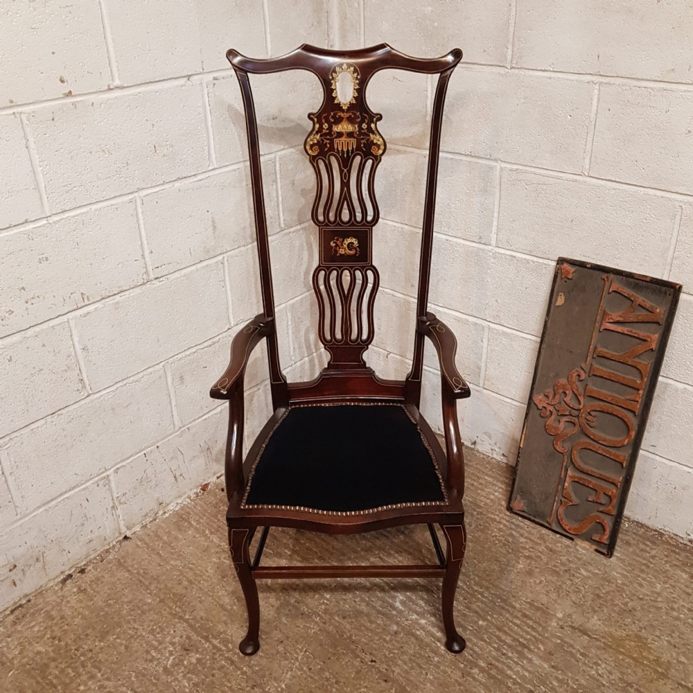A late 19th-century mahogany high-backed armchair featuring intricate floral marquetry inlay and a dark upholstered seat.