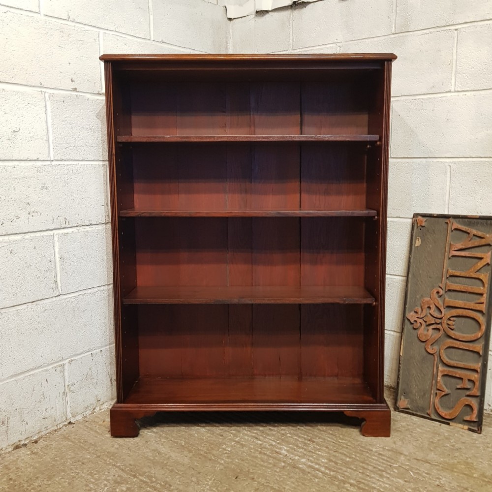 An Edwardian mahogany open bookcase featuring four tier shelf spaces, reeded vertical side moulding, and bracket feet.