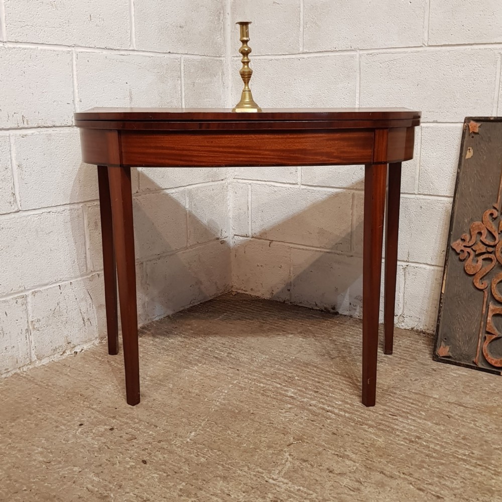 A Regency mahogany D-shaped fold-over games table supported by tapered legs.