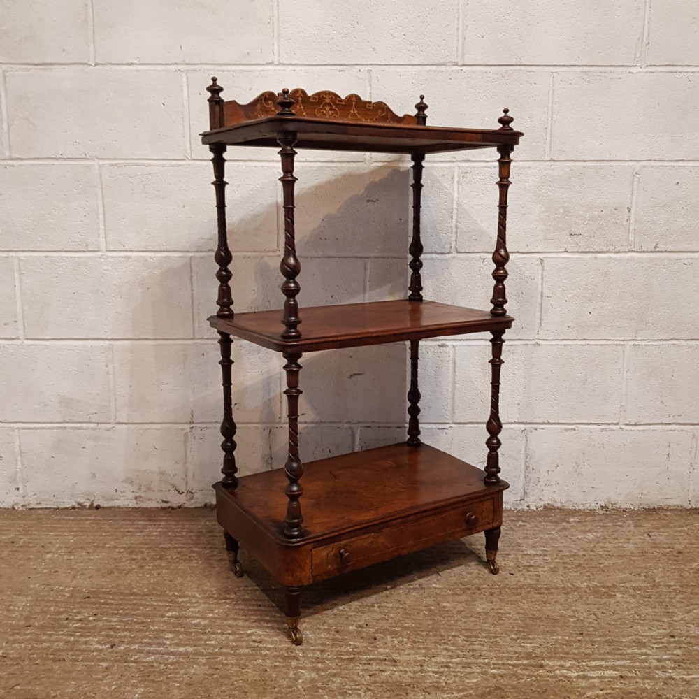 A three-tier Victorian burr walnut whatnot featuring spiral turned columns, an inlaid top gallery, a lower drawer, and brass castors.