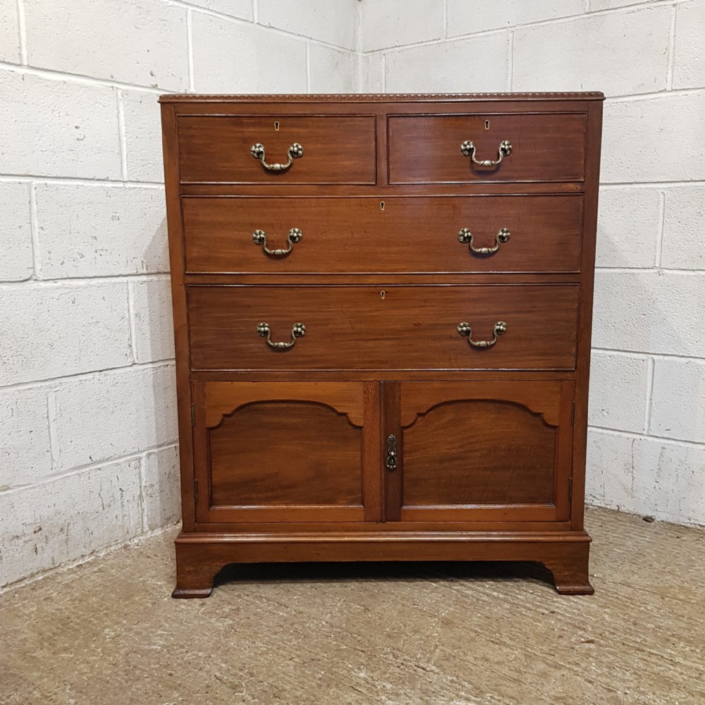 An Edwardian mahogany tallboy chest featuring two short drawers over two long drawers and a double-door cupboard base on bracket feet.