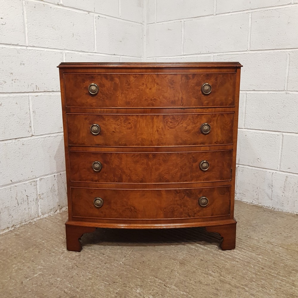 A 1920s burr walnut chest of drawers featuring four graduated bow-front drawers with brass ring handles and bracket feet.