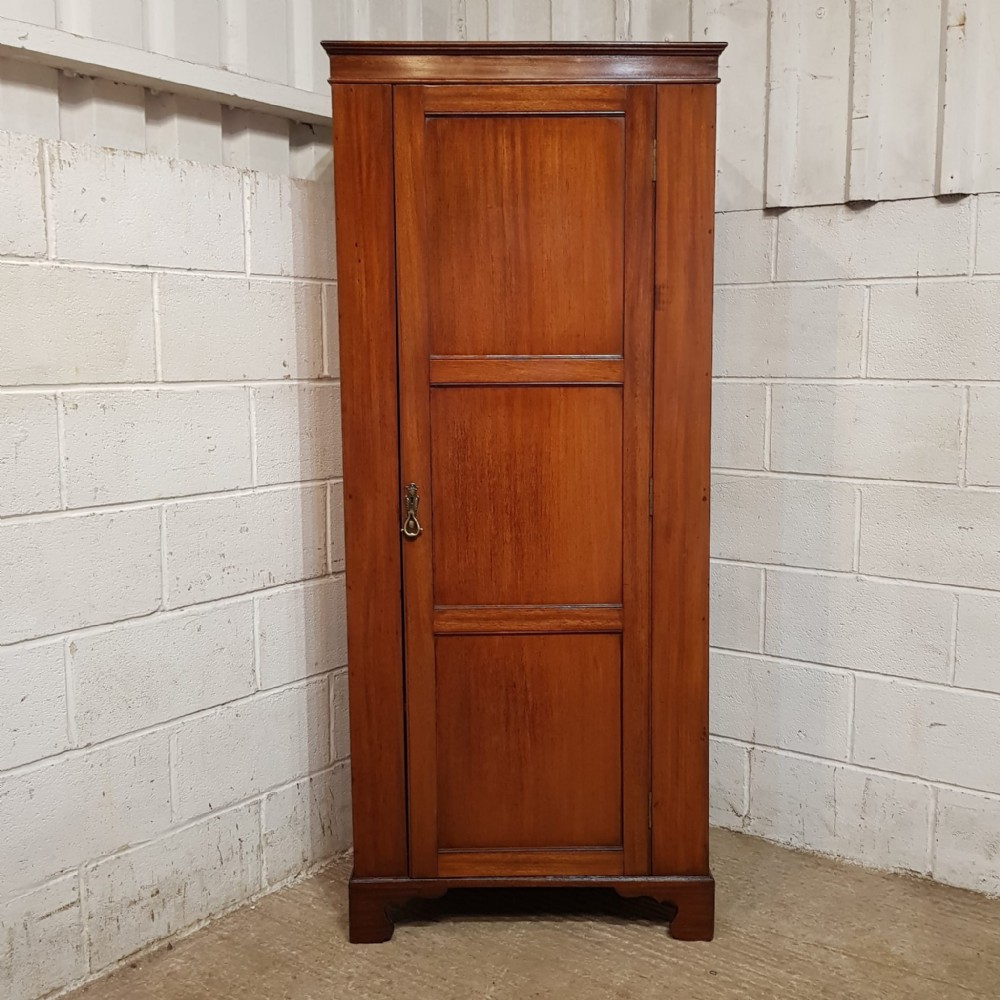 A tall, narrow mahogany sentry box wardrobe featuring a single three-panel door, brass handle, moulded top cornice, and bracket feet.