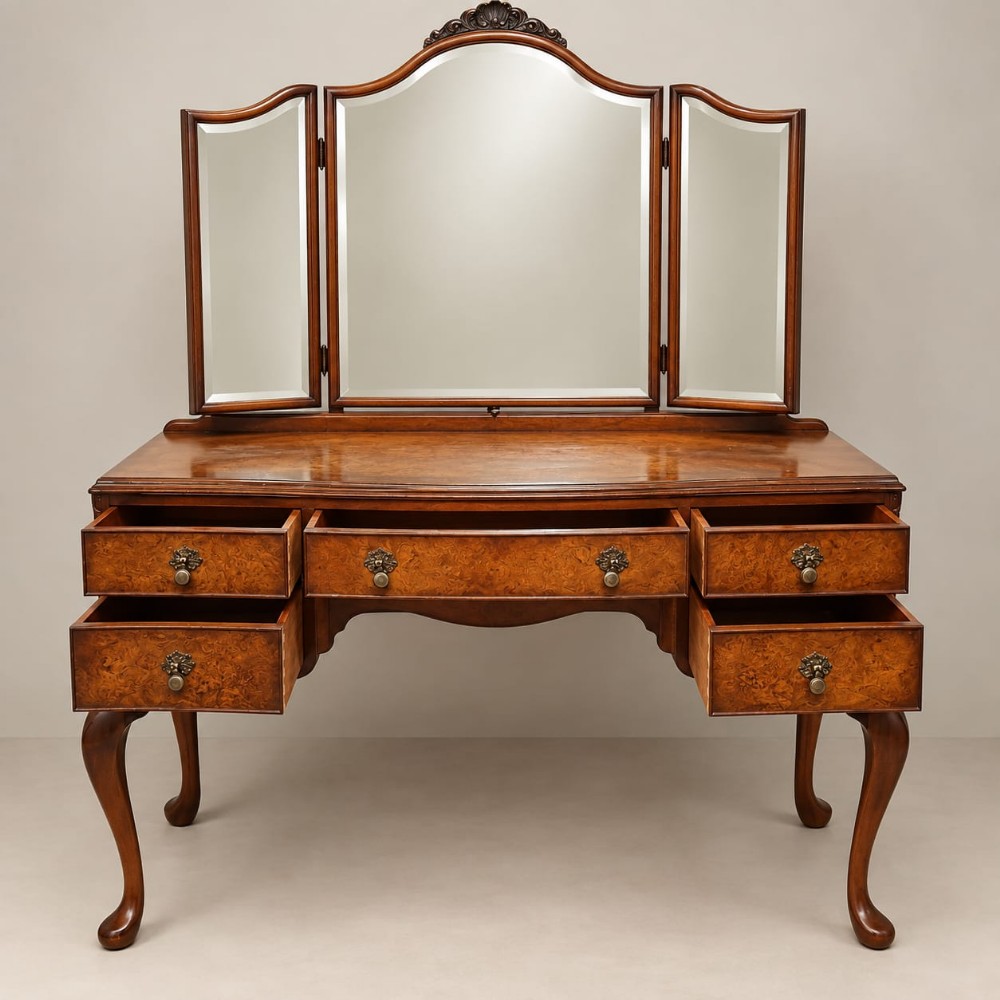 A burr walnut Queen Anne style dressing table featuring a serpentine front, five open drawers, brass handles, cabriole legs, and an attached three-piece mirror.