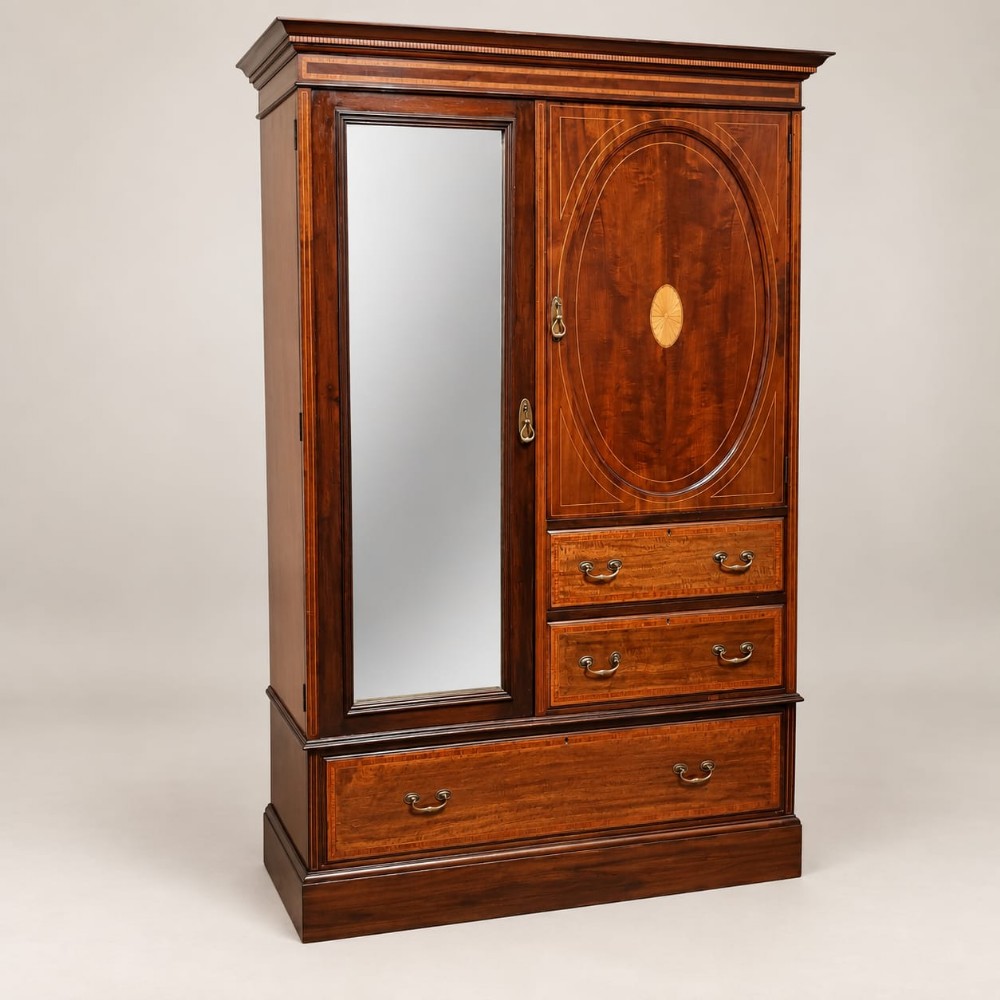 An Edwardian mahogany combination wardrobe featuring a full-length mirrored door, an inlaid cupboard, three drawers, and satinwood crossbanding.