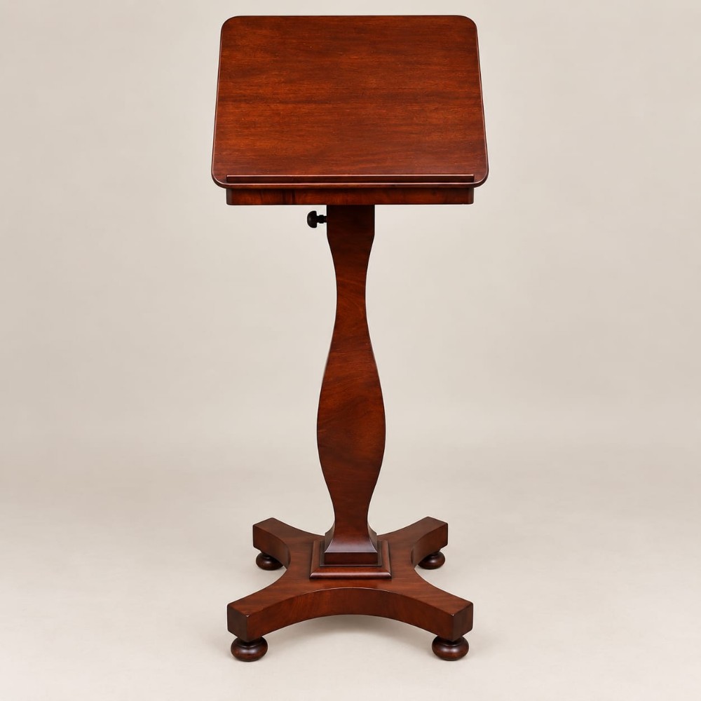 A Victorian mahogany music stand featuring an adjustable tilted rest, a turned shaped stem, and a quadform base with turned feet.