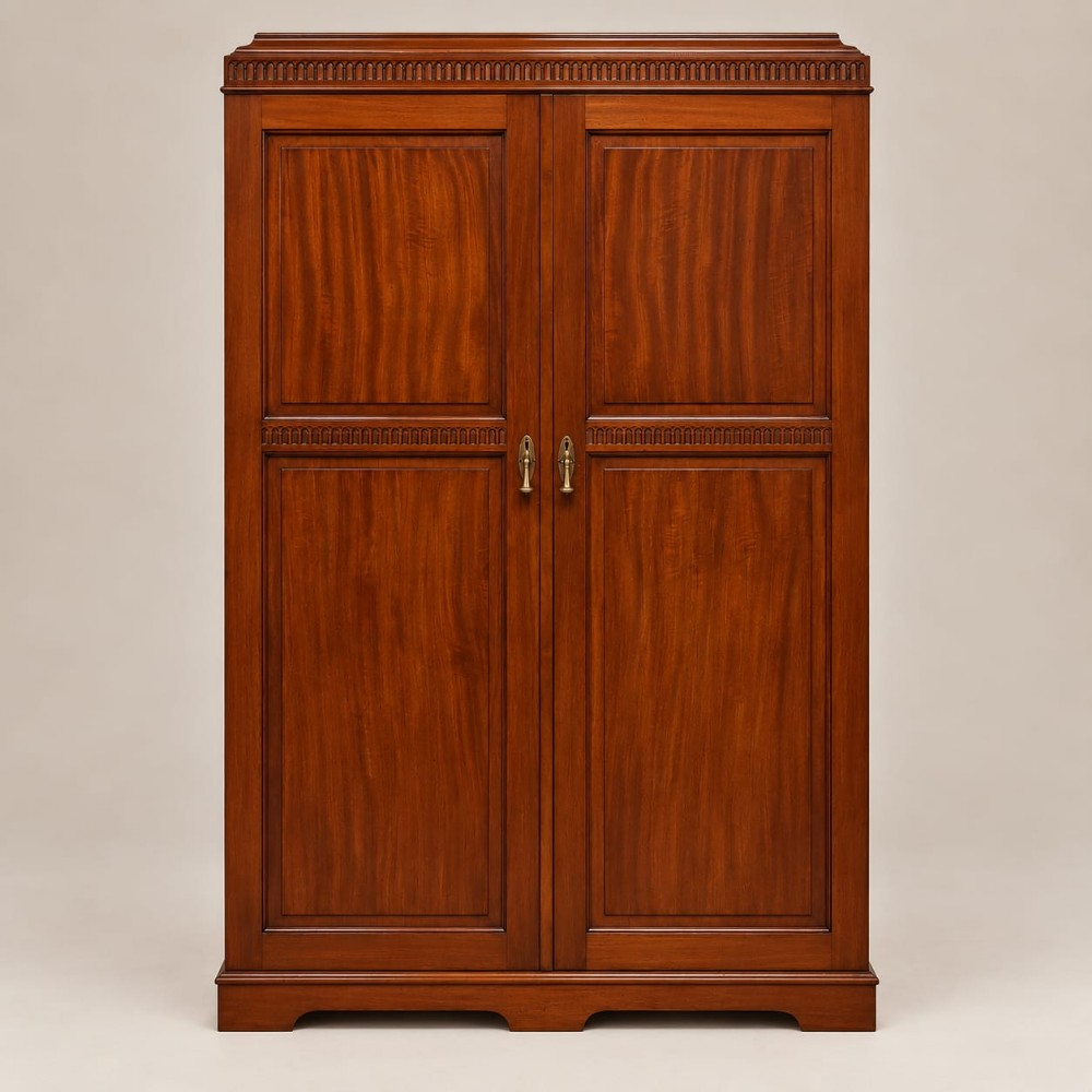An Edwardian double wardrobe constructed from warm brown mahogany featuring two full-length panelled doors and brass handles.