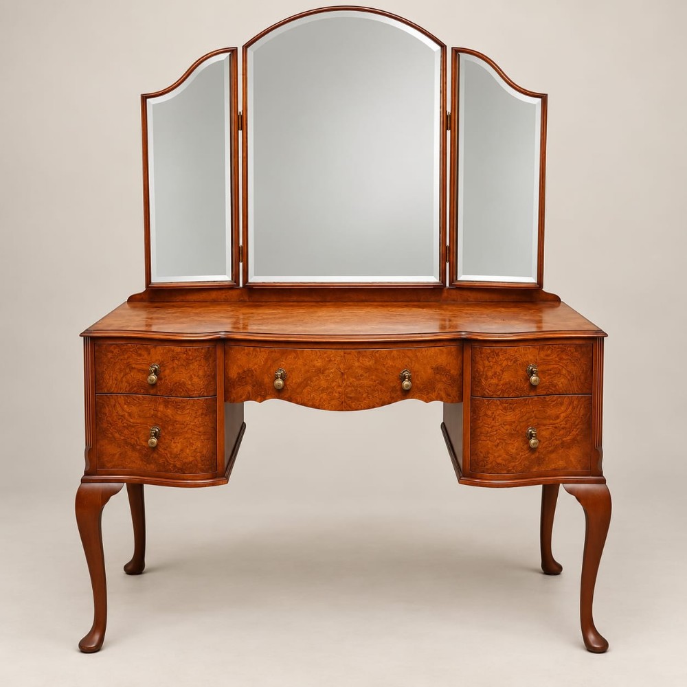 A 1920s burr walnut dressing table featuring a serpentine-fronted desk with five drawers, cabriole legs, brass handles, and a three-panel folding mirror.