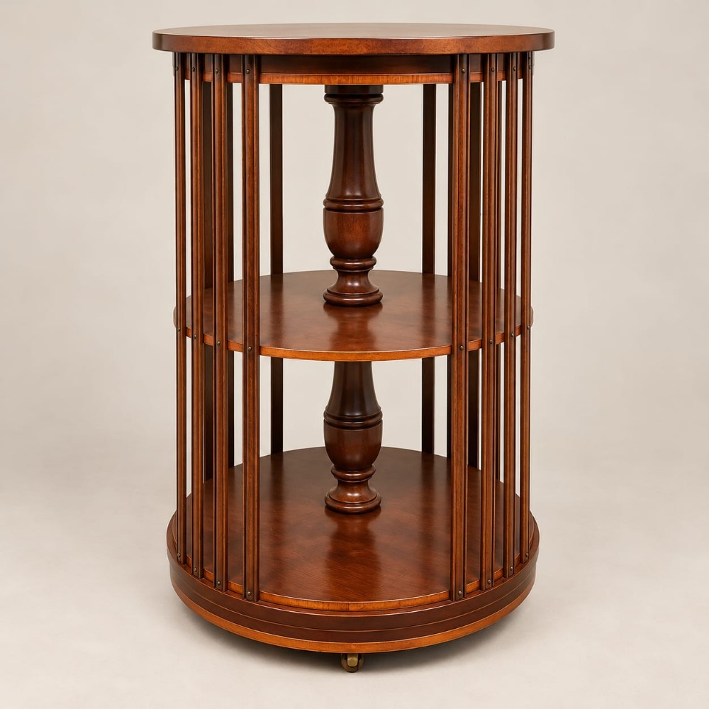 A circular mahogany three-tier revolving bookcase featuring vertical slatted sides, central turned columns, and a rotating base mounted on small castors.