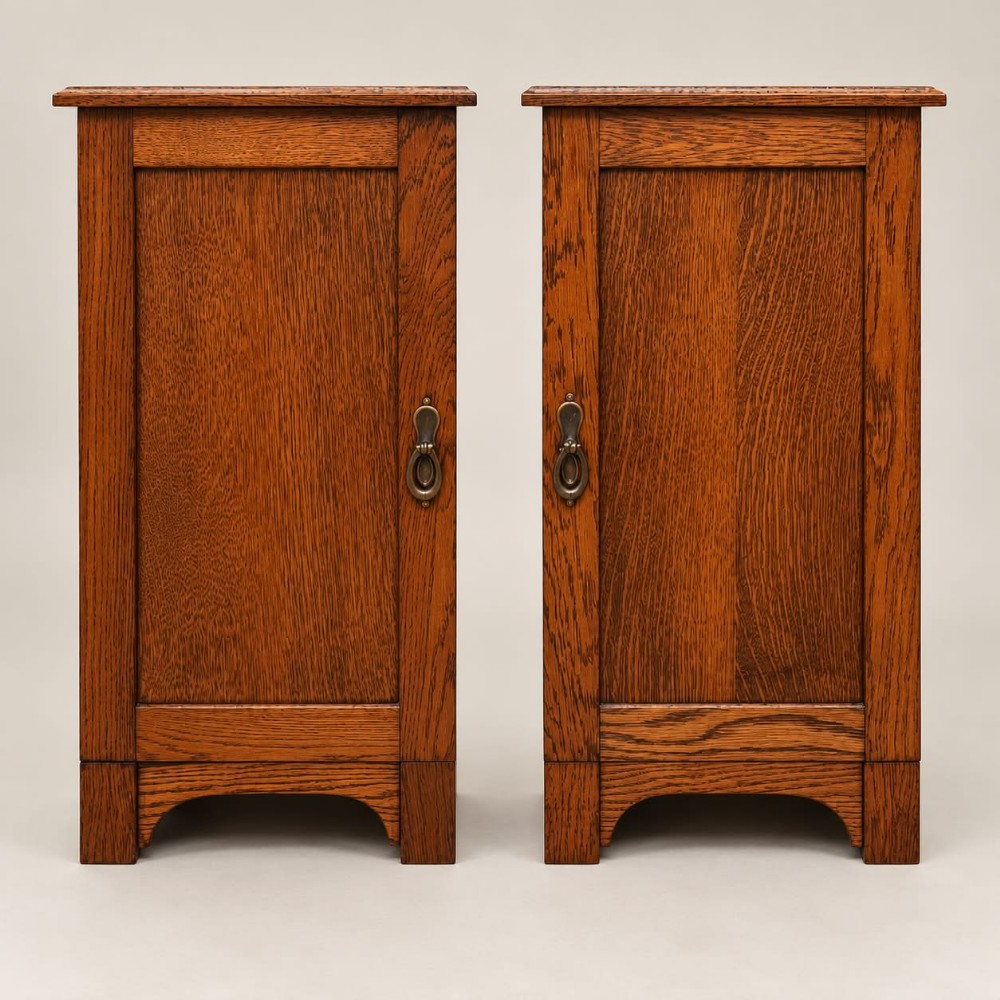A pair of medium oak bedside cabinets featuring single panelled doors, brass teardrop handles, and shaped aprons.