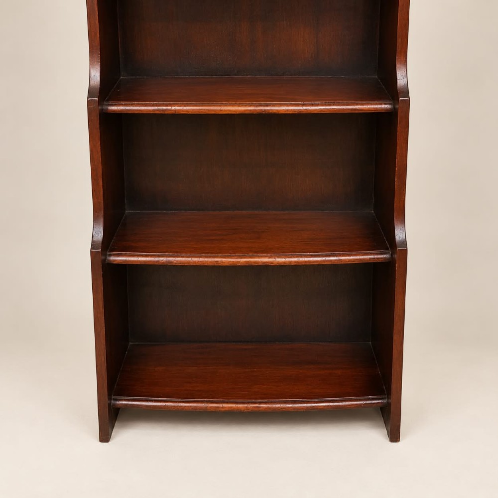 A tall and narrow dark oak waterfall bookcase circa 1920 with six open shelves graduating in depth. View V