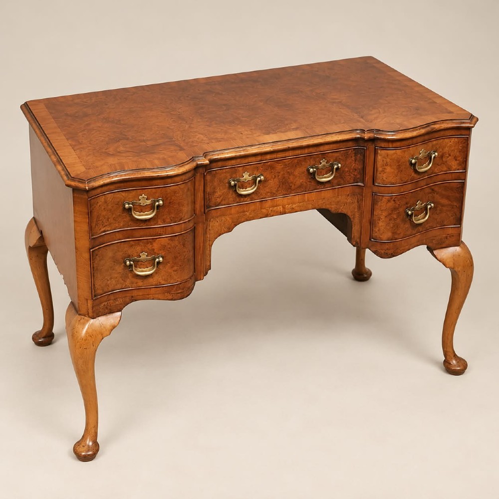 A 1920s burr walnut serpentine-fronted desk featuring five drawers with brass handles and cabriole legs. View III