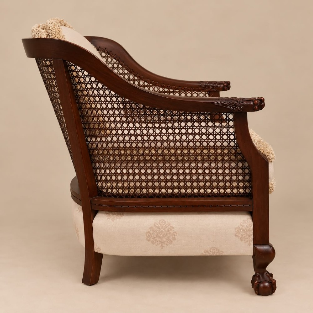 A pair of 1920s mahogany tub chairs featuring woven cane side panels, carved claw and ball feet, and cream upholstered cushions with matching circular accent pillows. View III