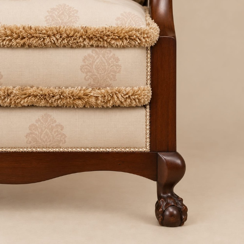 A pair of 1920s mahogany tub chairs featuring woven cane side panels, carved claw and ball feet, and cream upholstered cushions with matching circular accent pillows. View VI