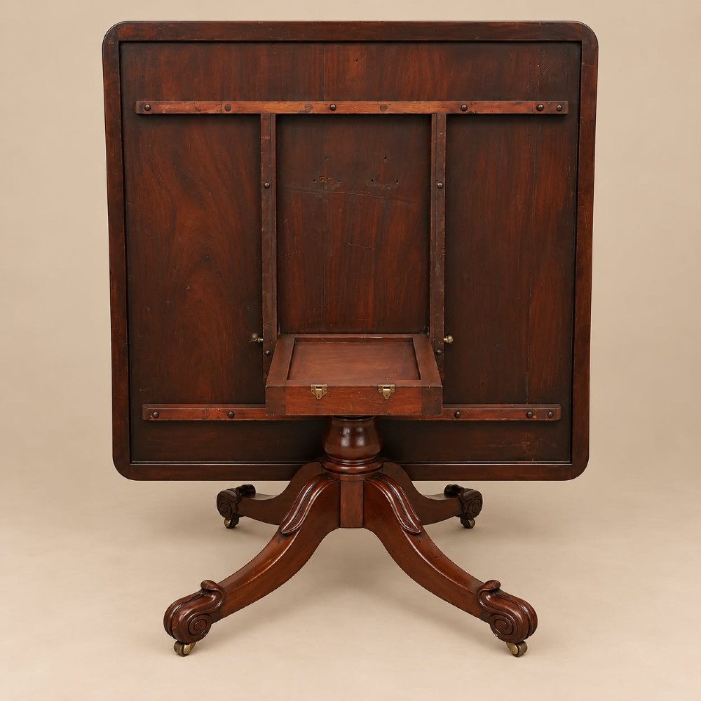 A late Georgian mahogany tilt-top dining table featuring a central turned pedestal and splayed quadform legs with brass castors. View II