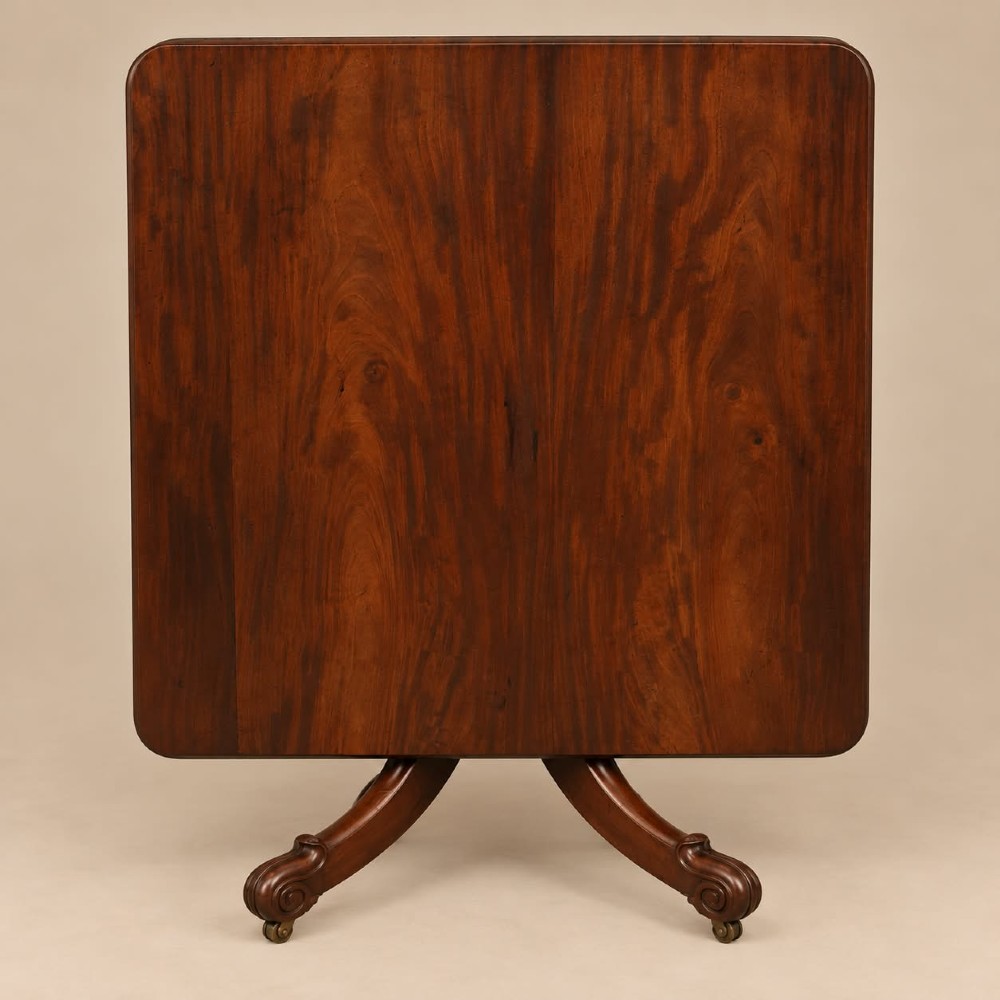 A late Georgian mahogany tilt-top dining table featuring a central turned pedestal and splayed quadform legs with brass castors. View VI