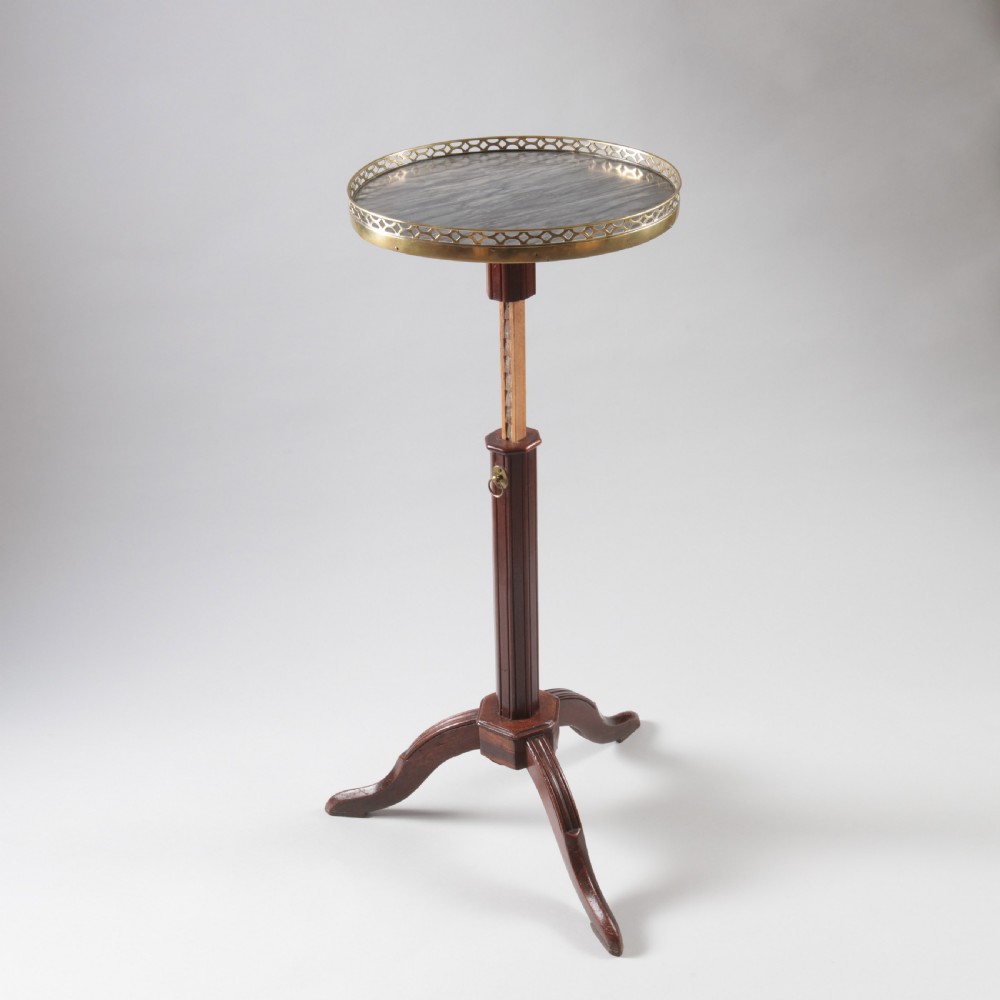 A Louis XVI style mahogany wine table featuring a circular grey marble top enclosed by a pierced brass gallery, supported on a fluted central pedestal and tripod legs. View IV