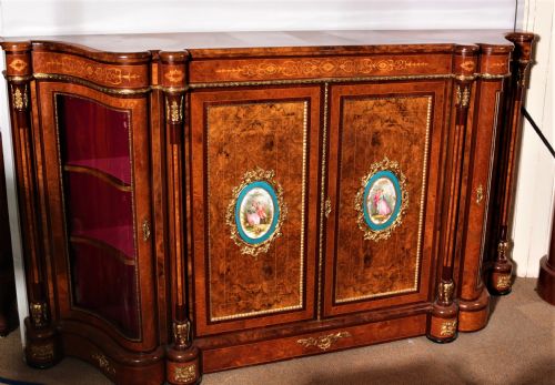 fig 1. An antique Victorian burr walnut credenza featuring glazed end display doors, intricate marquetry inlay, gilt-metal mounts, and central cabinet doors adorned with oval painted porcelain plaques.