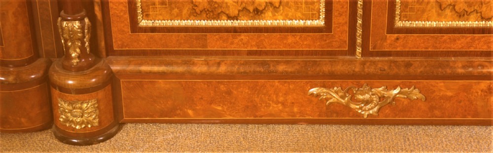 An antique Victorian burr walnut credenza featuring glazed end display doors, intricate marquetry inlay, gilt-metal mounts, and central cabinet doors adorned with oval painted porcelain plaques. View VII