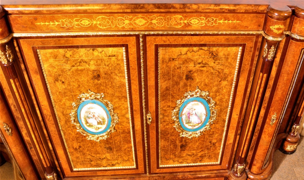 An antique Victorian burr walnut credenza featuring glazed end display doors, intricate marquetry inlay, gilt-metal mounts, and central cabinet doors adorned with oval painted porcelain plaques. View XIII