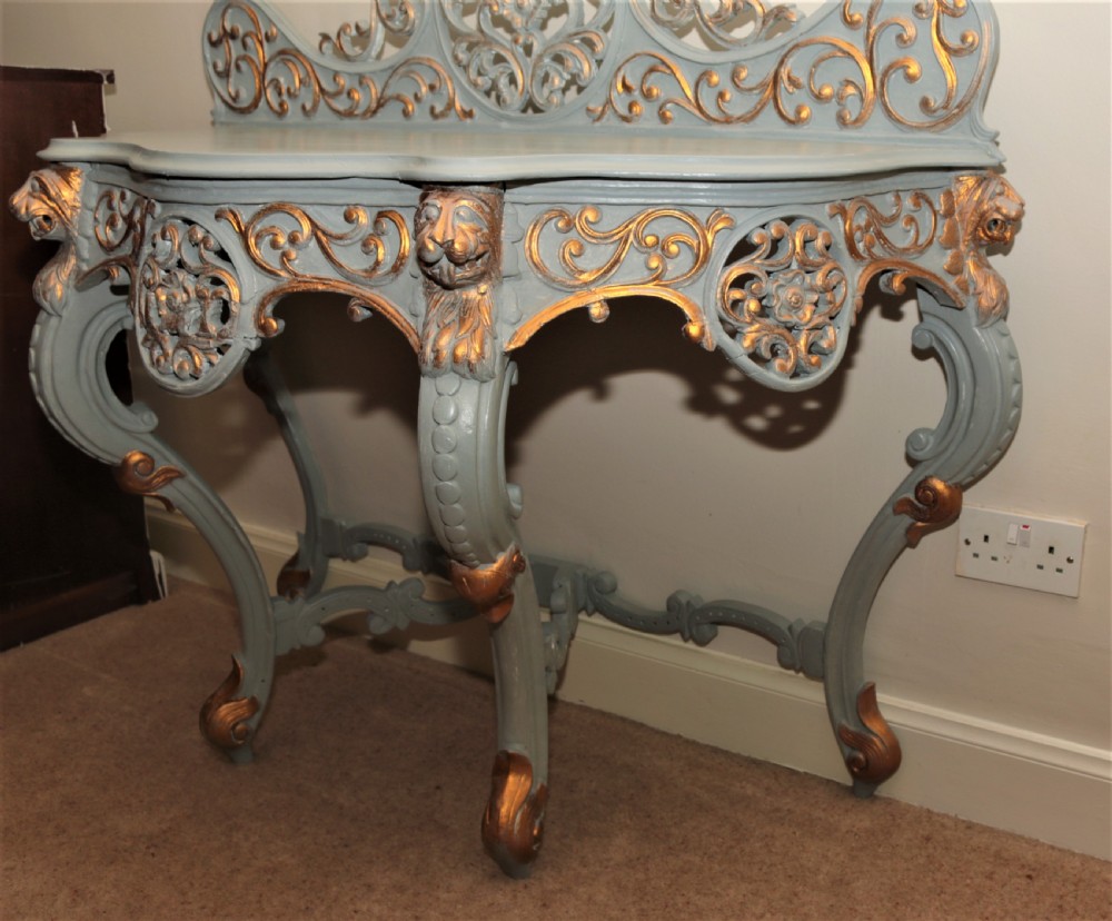 A Mid-Victorian painted grey and parcel-gilt console table featuring an intricate pierced scrollwork crest, lion mask carvings, and cabriole legs. View II