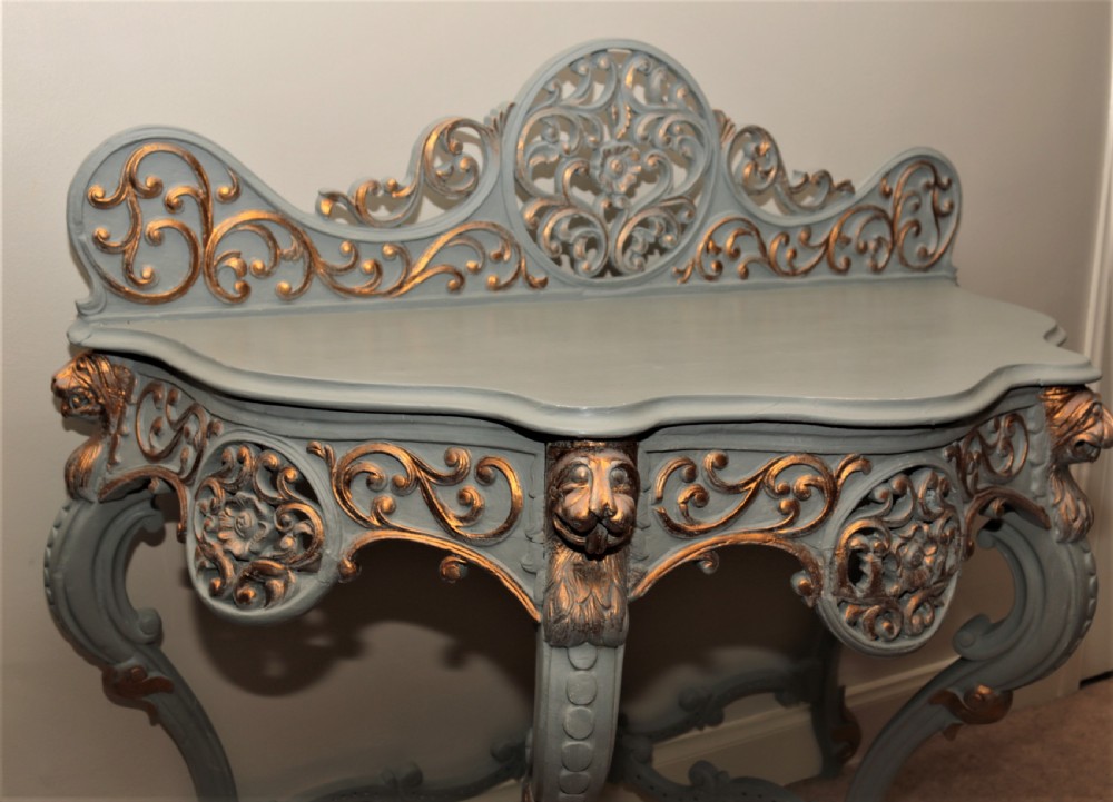 A Mid-Victorian painted grey and parcel-gilt console table featuring an intricate pierced scrollwork crest, lion mask carvings, and cabriole legs. View IV