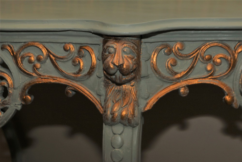 A Mid-Victorian painted grey and parcel-gilt console table featuring an intricate pierced scrollwork crest, lion mask carvings, and cabriole legs. View V