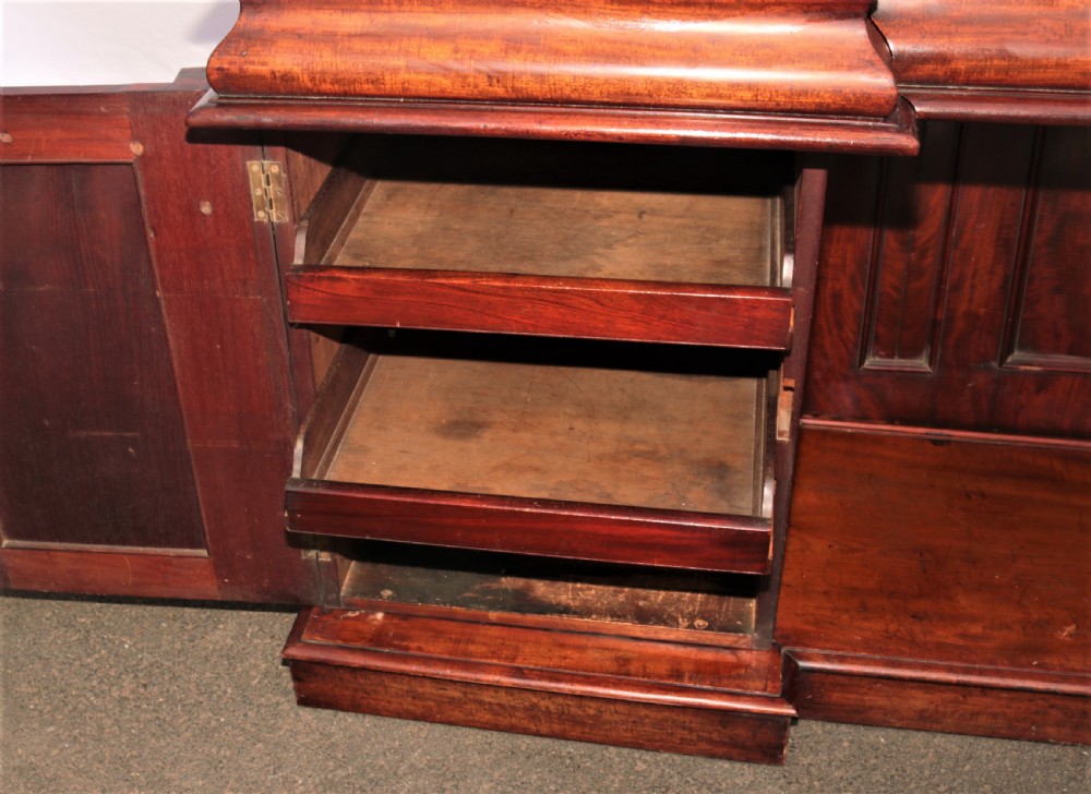 A Victorian dark mahogany sideboard featuring a large carved rococo backboard, flat serving surface, and two pedestal side cupboards. View XIII