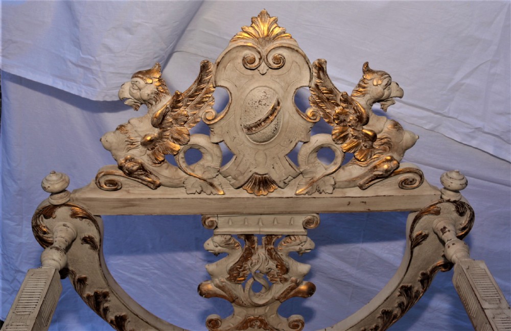 A pair of painted and carved giltwood Savonarola chairs with curved X-frames, ornate carved crests, and yellow patterned fabric seat cushions. View III