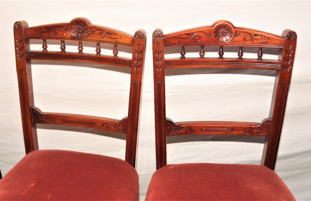 A set of six Victorian mahogany dining chairs featuring carved top rails with turned spindles, turned front legs, and red velvet padded seats. View II