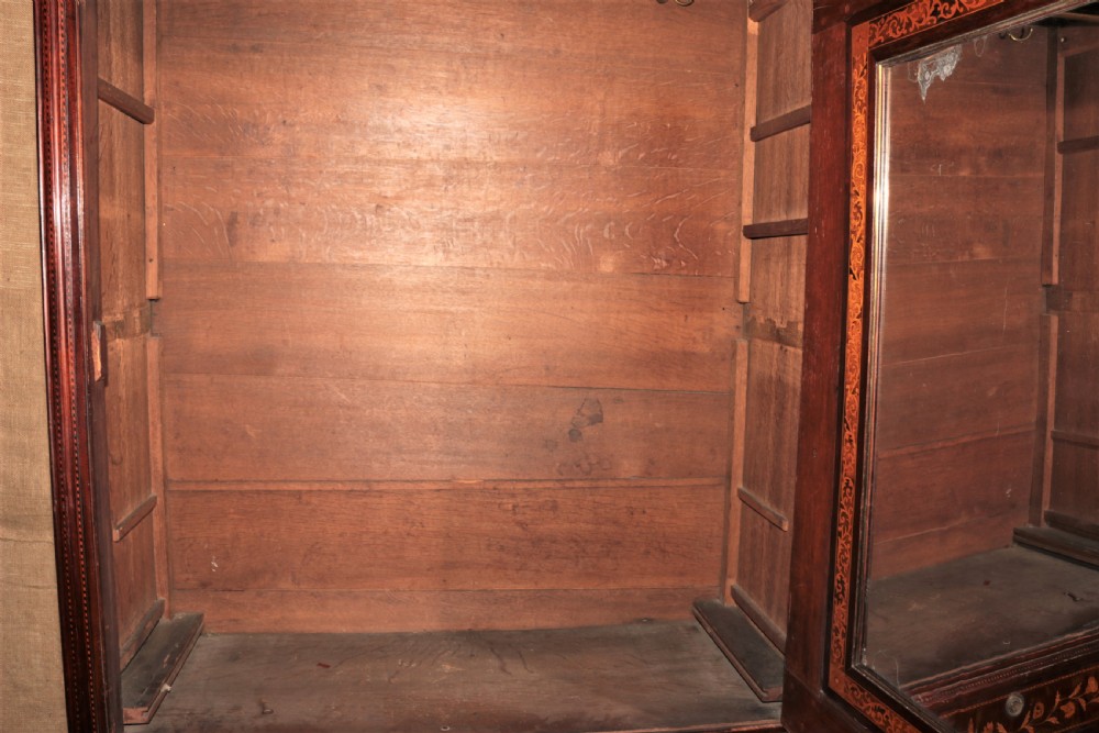 A tall dark mahogany wardrobe decorated with intricate light wood floral marquetry, featuring large panelled upper doors and a lower drawer section. View VIII
