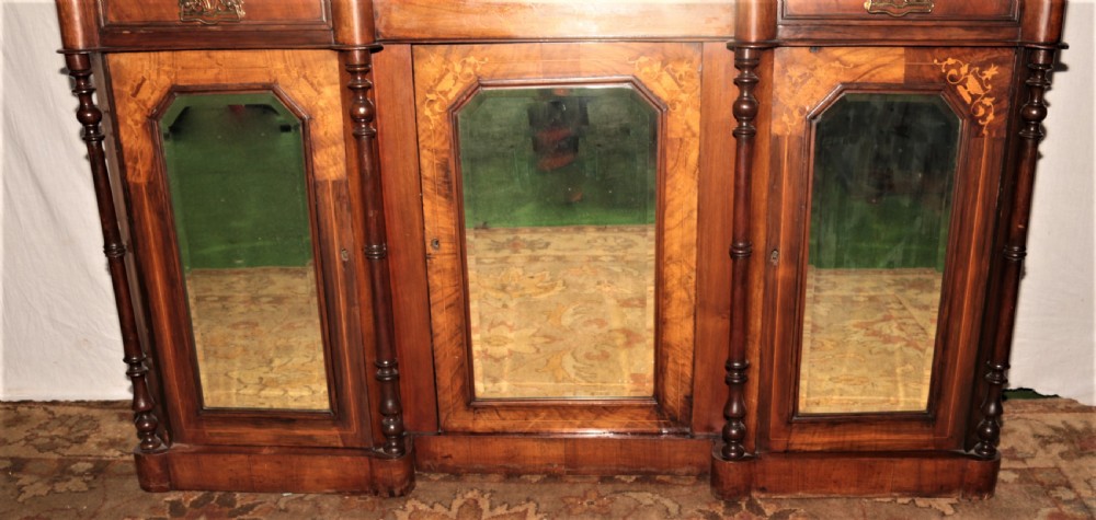 An ornate Victorian walnut chiffonier featuring a central arched mirror topped with a carved eagle crest, flanked by raised side shelves with oval mirror panels and cupboard doors below. View III