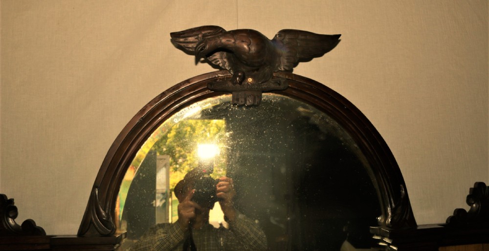 An ornate Victorian walnut chiffonier featuring a central arched mirror topped with a carved eagle crest, flanked by raised side shelves with oval mirror panels and cupboard doors below. View VII