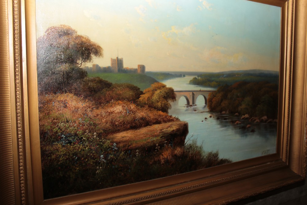 A framed landscape oil painting on canvas depicting Richmond Castle, a stone river bridge, and dense foliage beneath a soft blue sky.