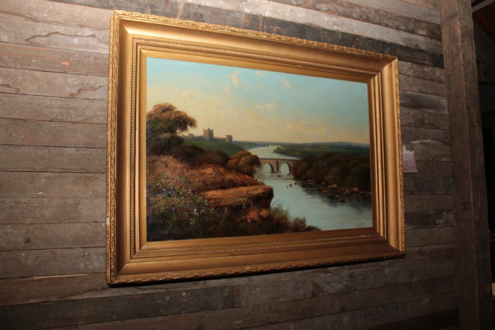 A framed landscape oil painting on canvas depicting Richmond Castle, a stone river bridge, and dense foliage beneath a soft blue sky. View X