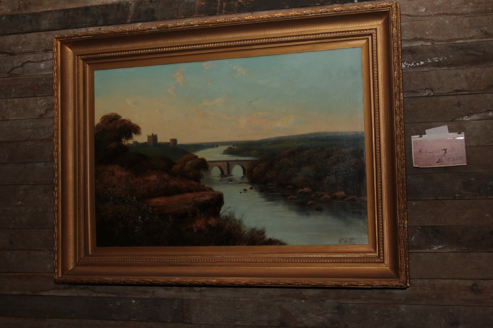 A framed landscape oil painting on canvas depicting Richmond Castle, a stone river bridge, and dense foliage beneath a soft blue sky. View XI