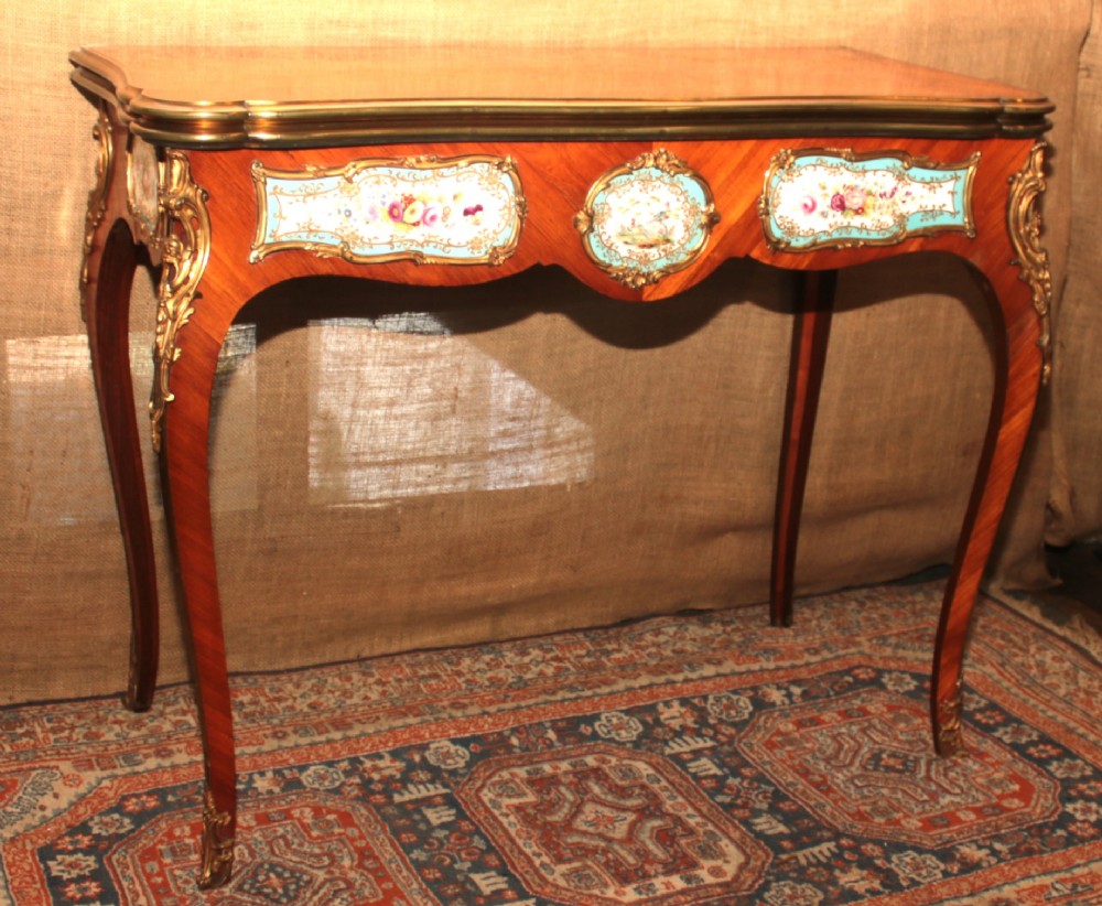 A mid-Victorian kingwood games table featuring cabriole legs, ornate gilt-bronze ormolu mounts, and inlaid porcelain plaques depicting floral scenes.