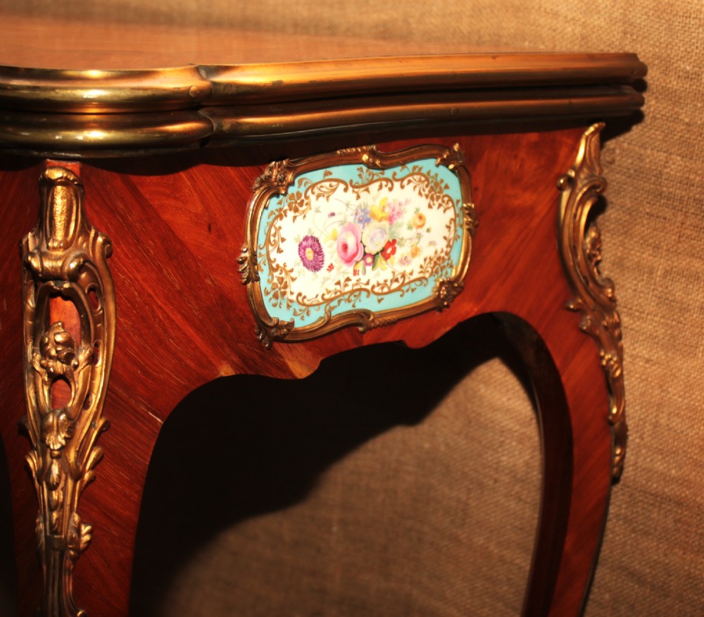 A mid-Victorian kingwood games table featuring cabriole legs, ornate gilt-bronze ormolu mounts, and inlaid porcelain plaques depicting floral scenes. View V