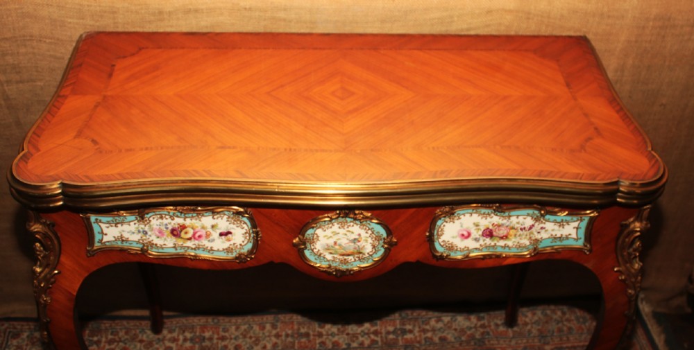 A mid-Victorian kingwood games table featuring cabriole legs, ornate gilt-bronze ormolu mounts, and inlaid porcelain plaques depicting floral scenes. View XIV
