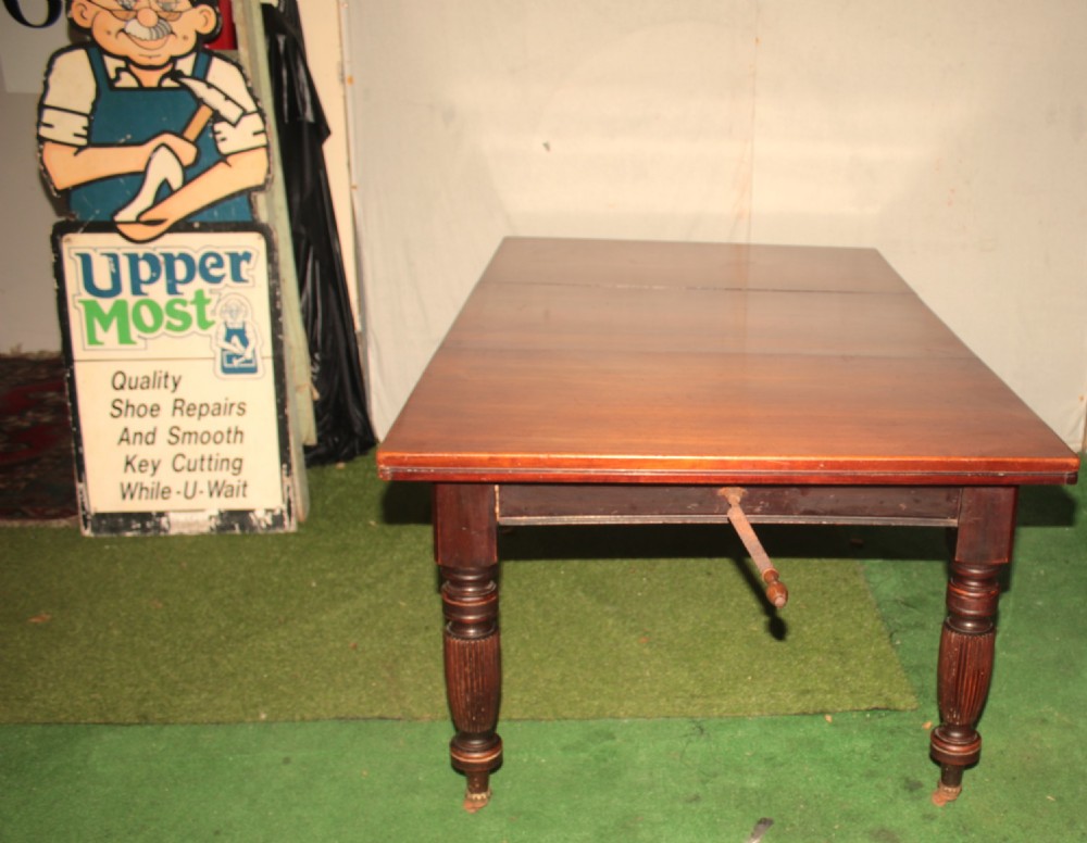 A late Victorian mahogany extending dining table featuring reeded turned legs on castors with a rectangular top. View VI