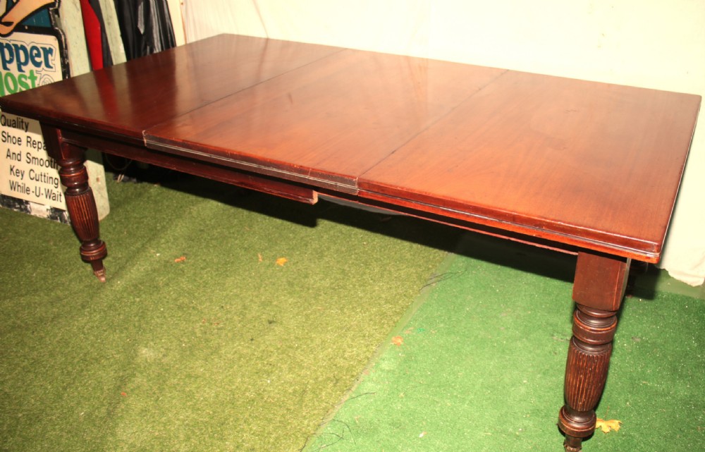 A late Victorian mahogany extending dining table featuring reeded turned legs on castors with a rectangular top. View VIII